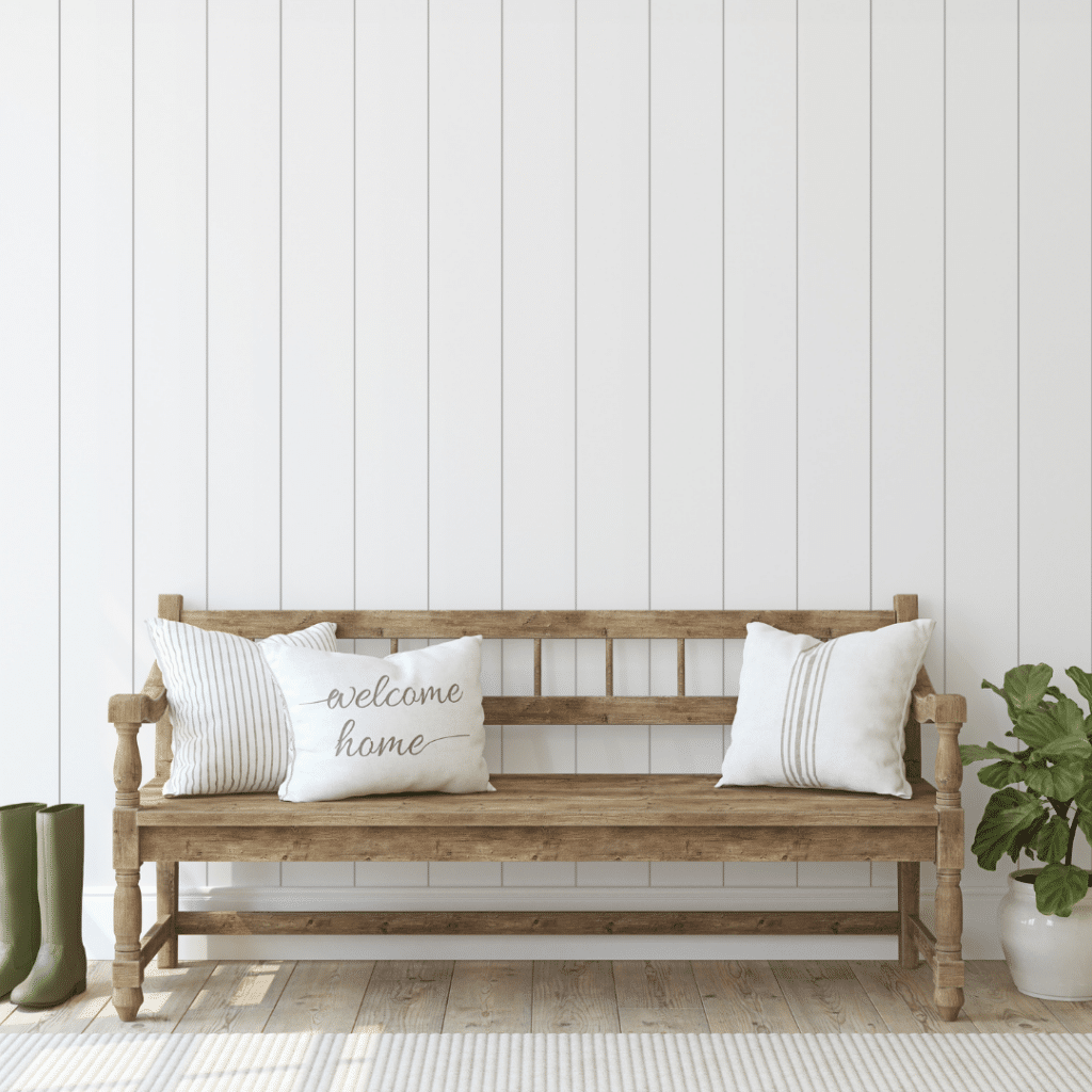 Illustrating the organization idea of the usefulness of a bench in the entryway. A wooden bench with three pillows in the entryway of a home.